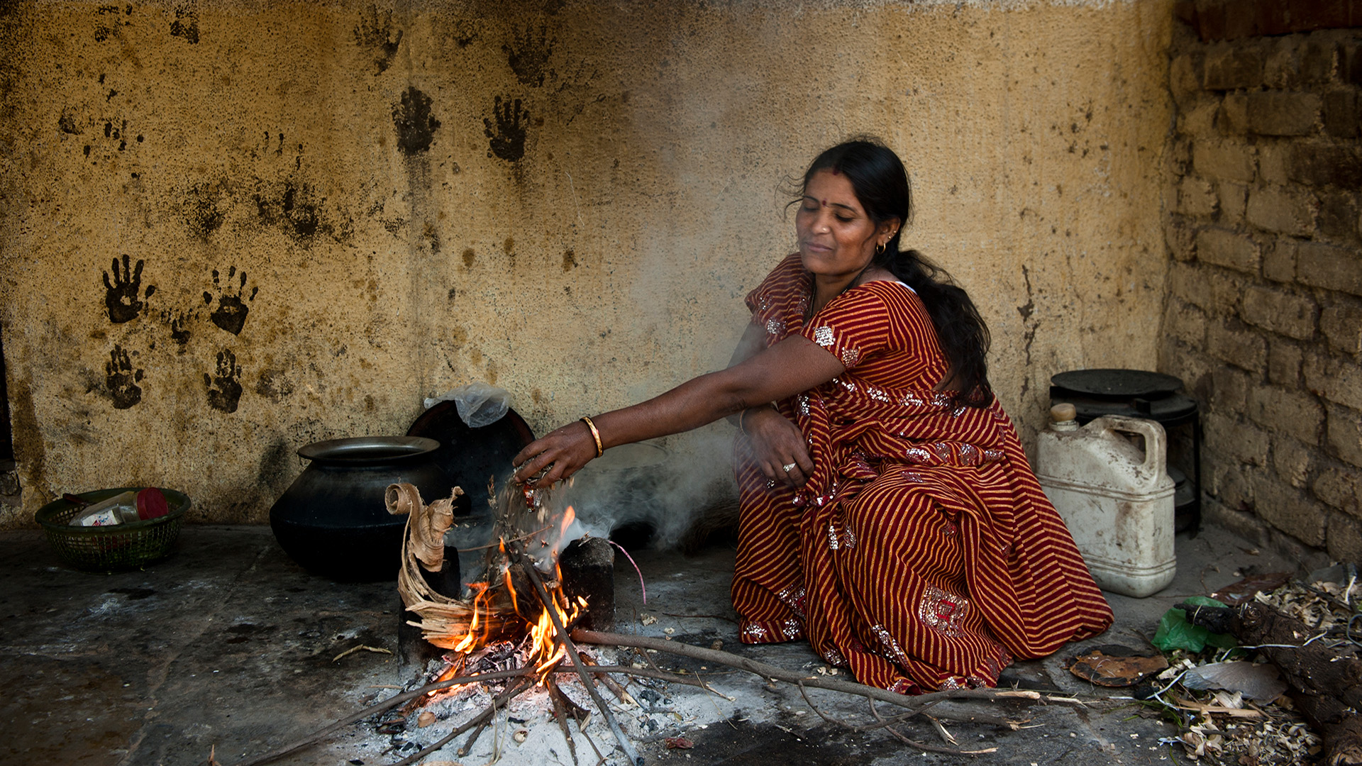 A woman cooking using woodfuel