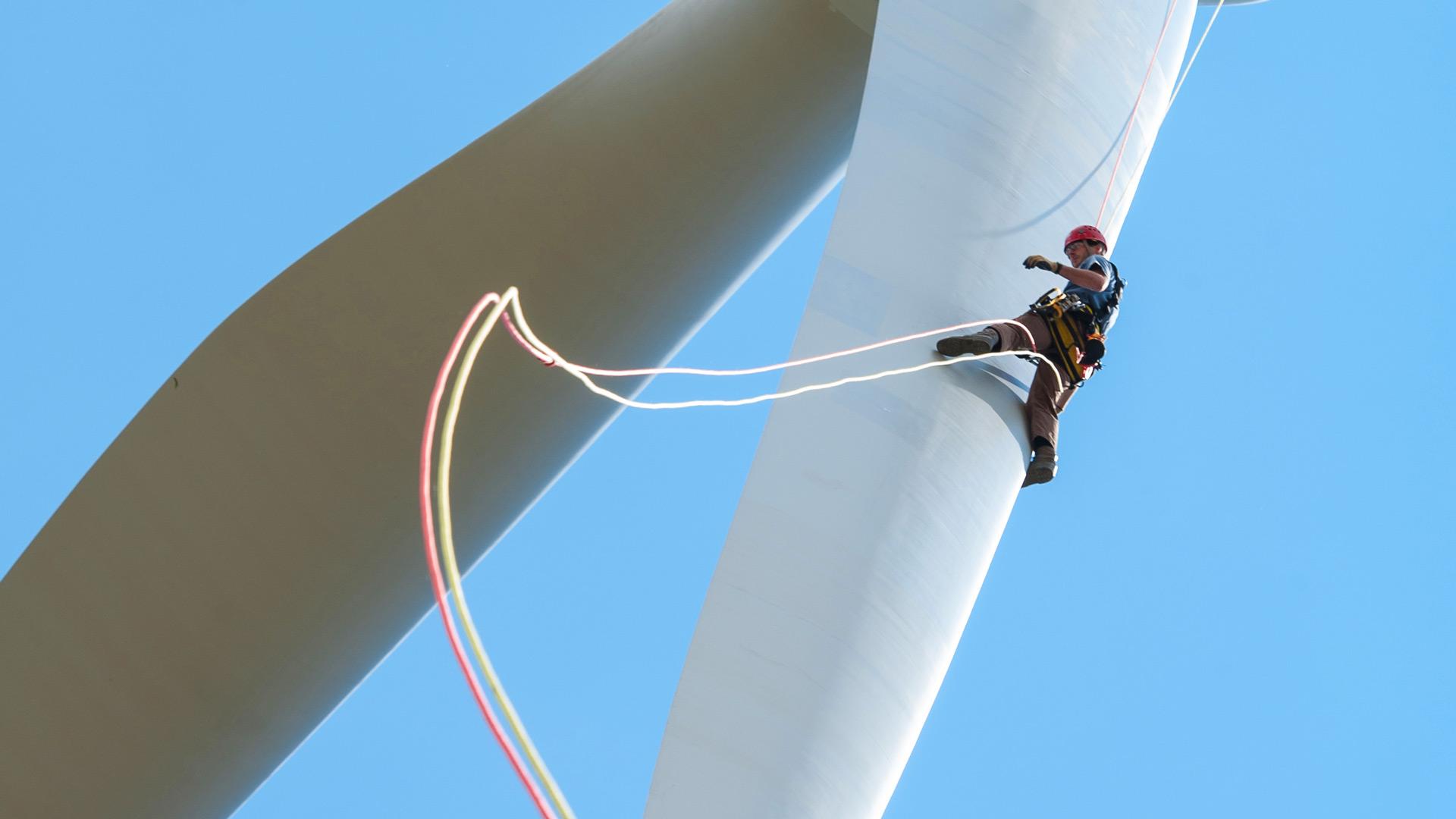 Worker rapelling down a wind turbine blade